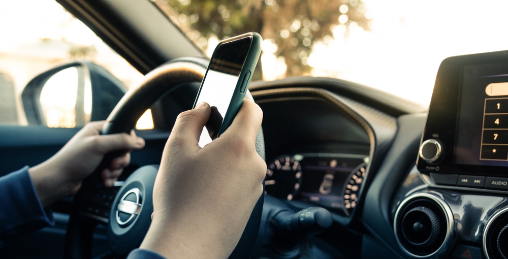 close up of distracted driver using smartphone behind the wheel