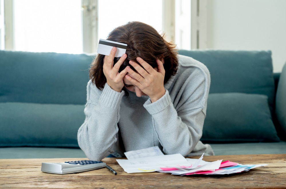 distressed person at coffee table with bills piled.